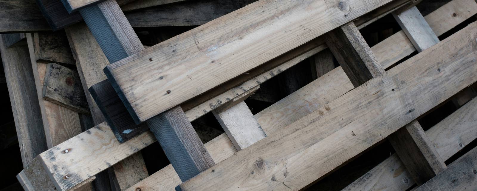 A loose pile of weathered gray wooden pallets